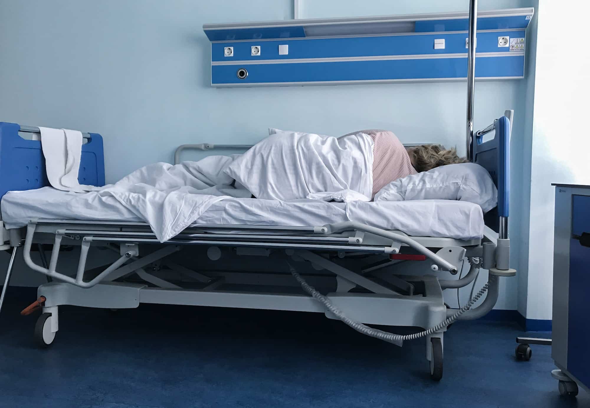 Hospital room. A patient is sleeping on the bed facing the wall