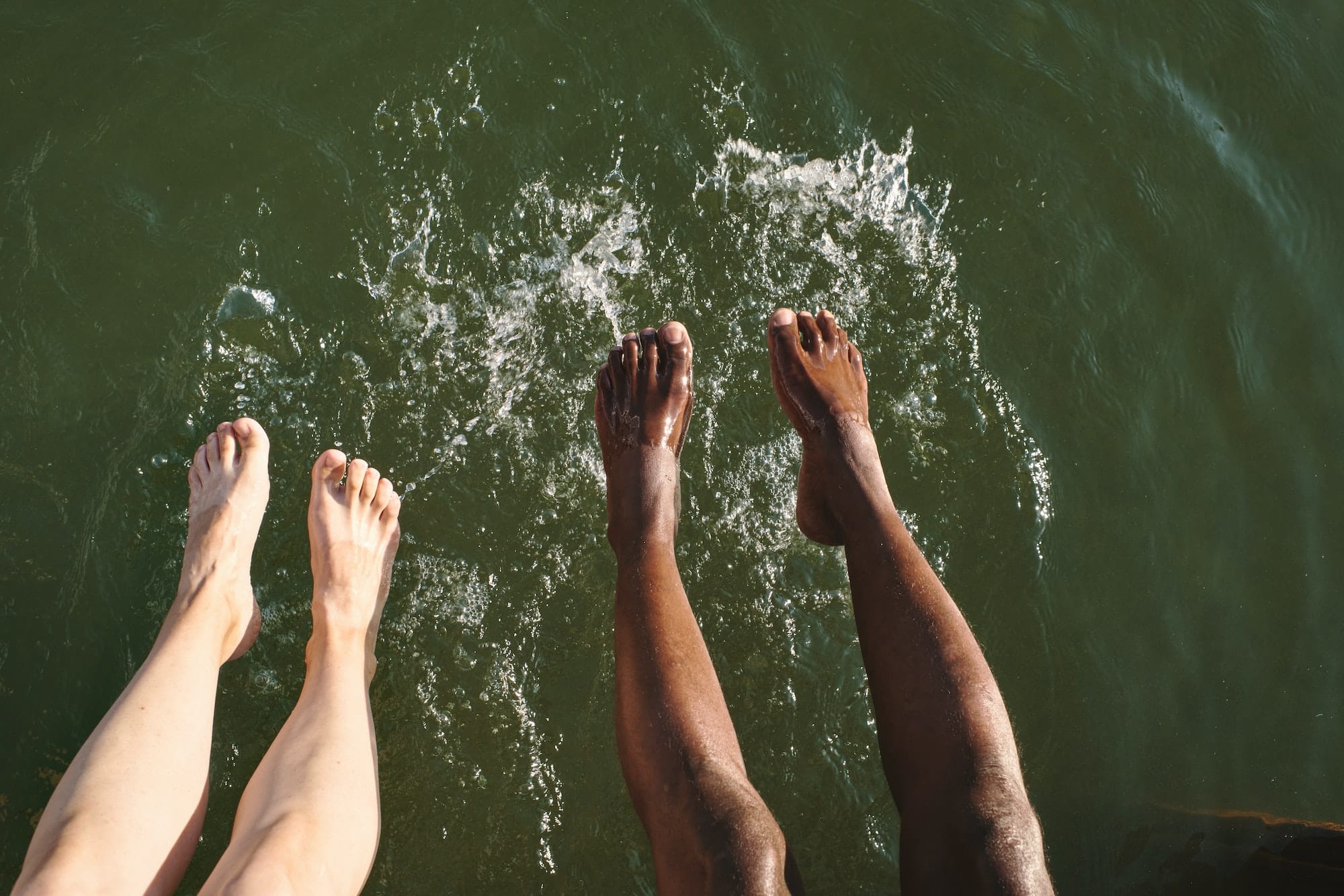 Overview of legs of young intercultural couple splashing water