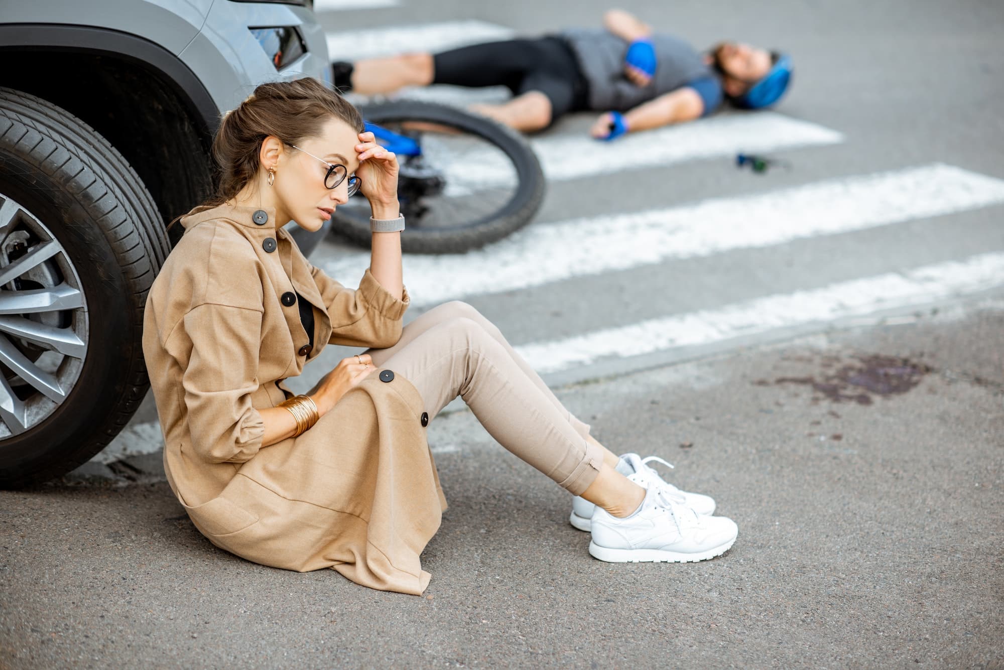 Sad woman driver and injured man after the road accident