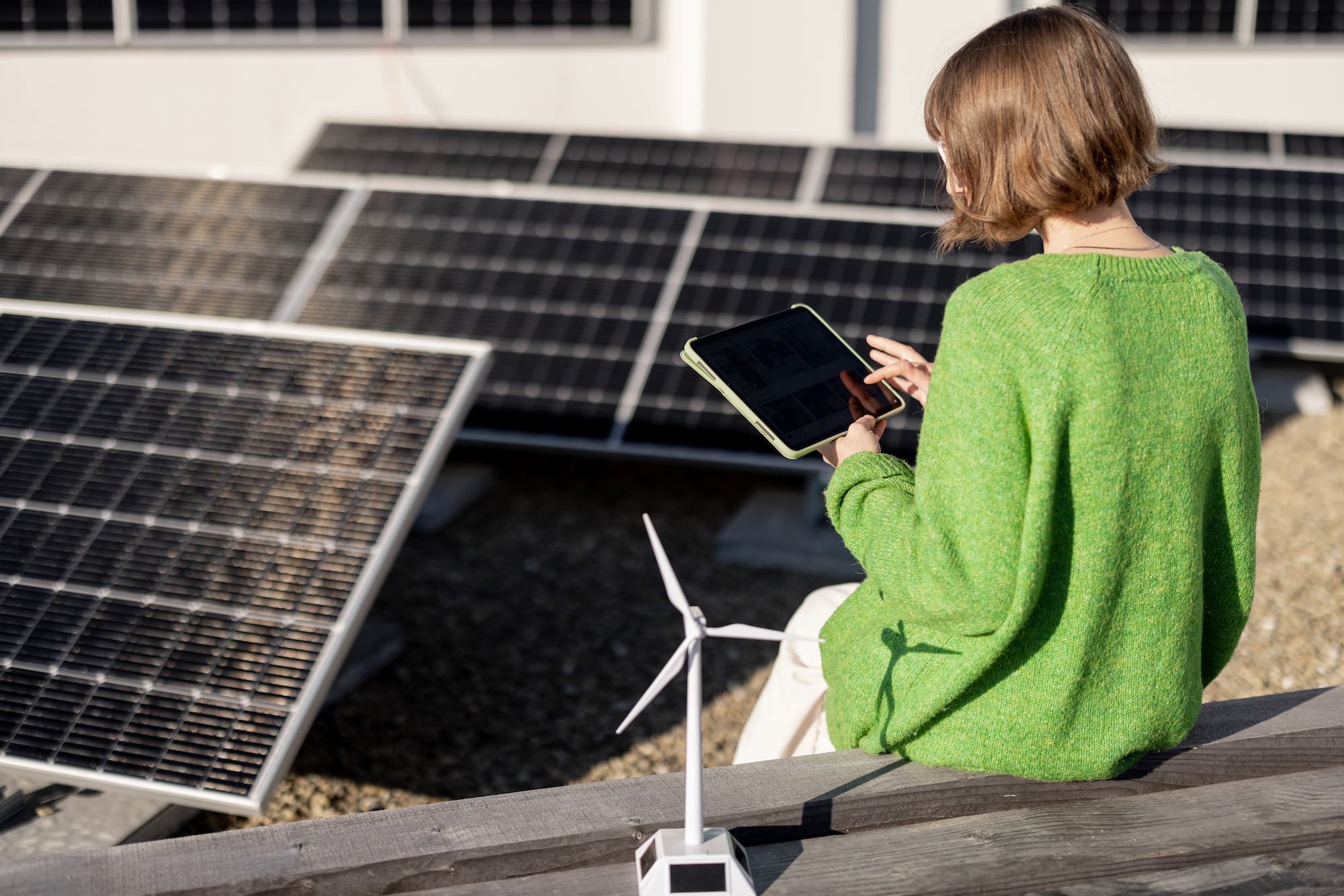 Woman monitors energy production from the solar power plant with a digital tablet