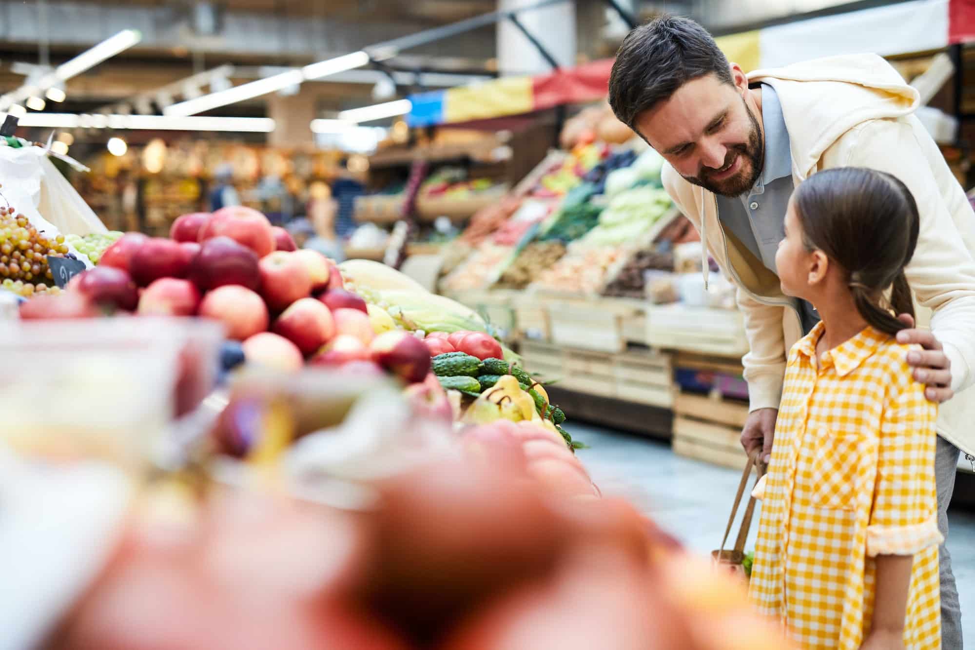 Careful father asking daughter to choose organic food at farmers market