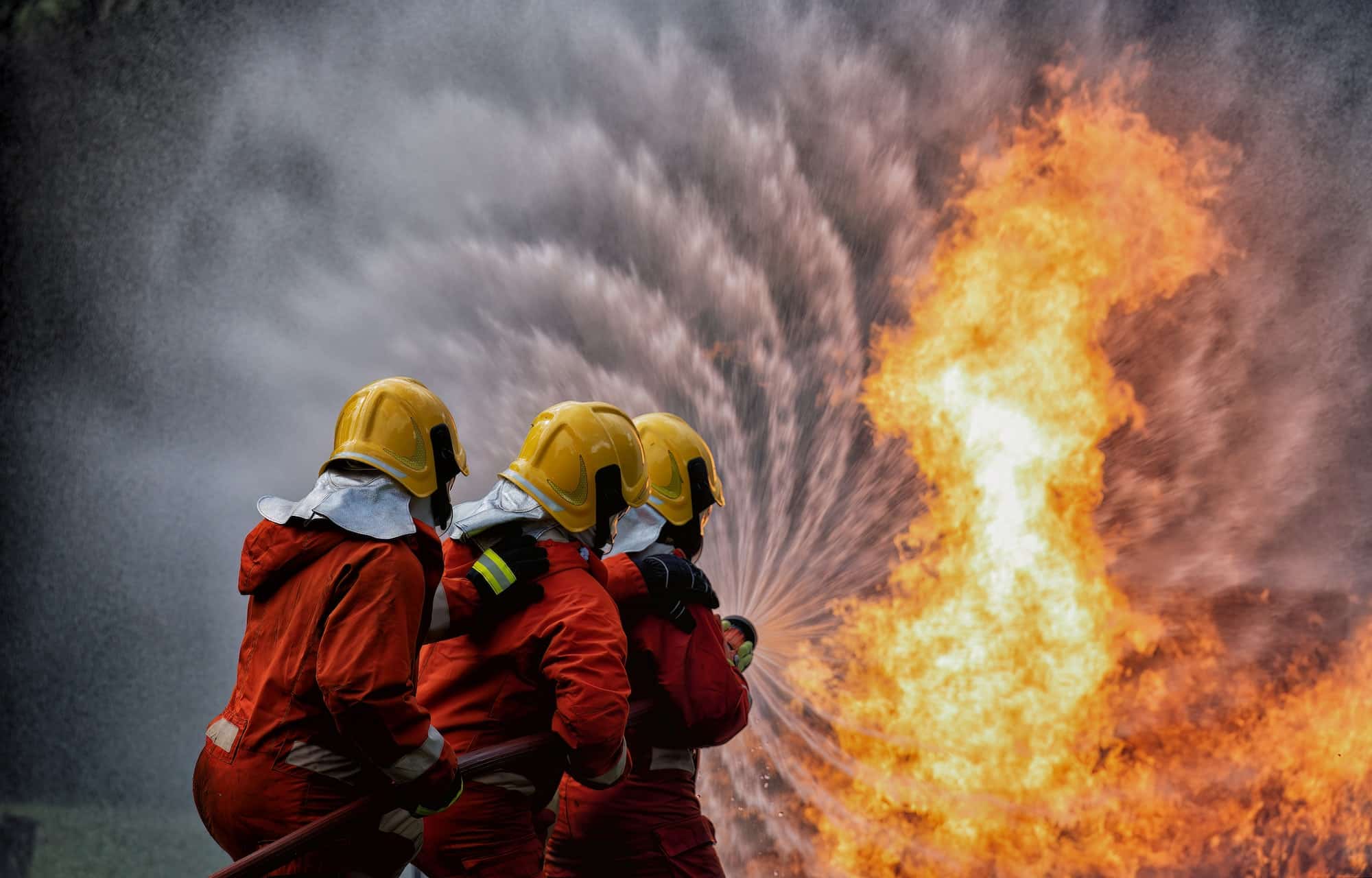 fire fighter team on training with gas and oil fire hold hose spray jet water spray to extinguish