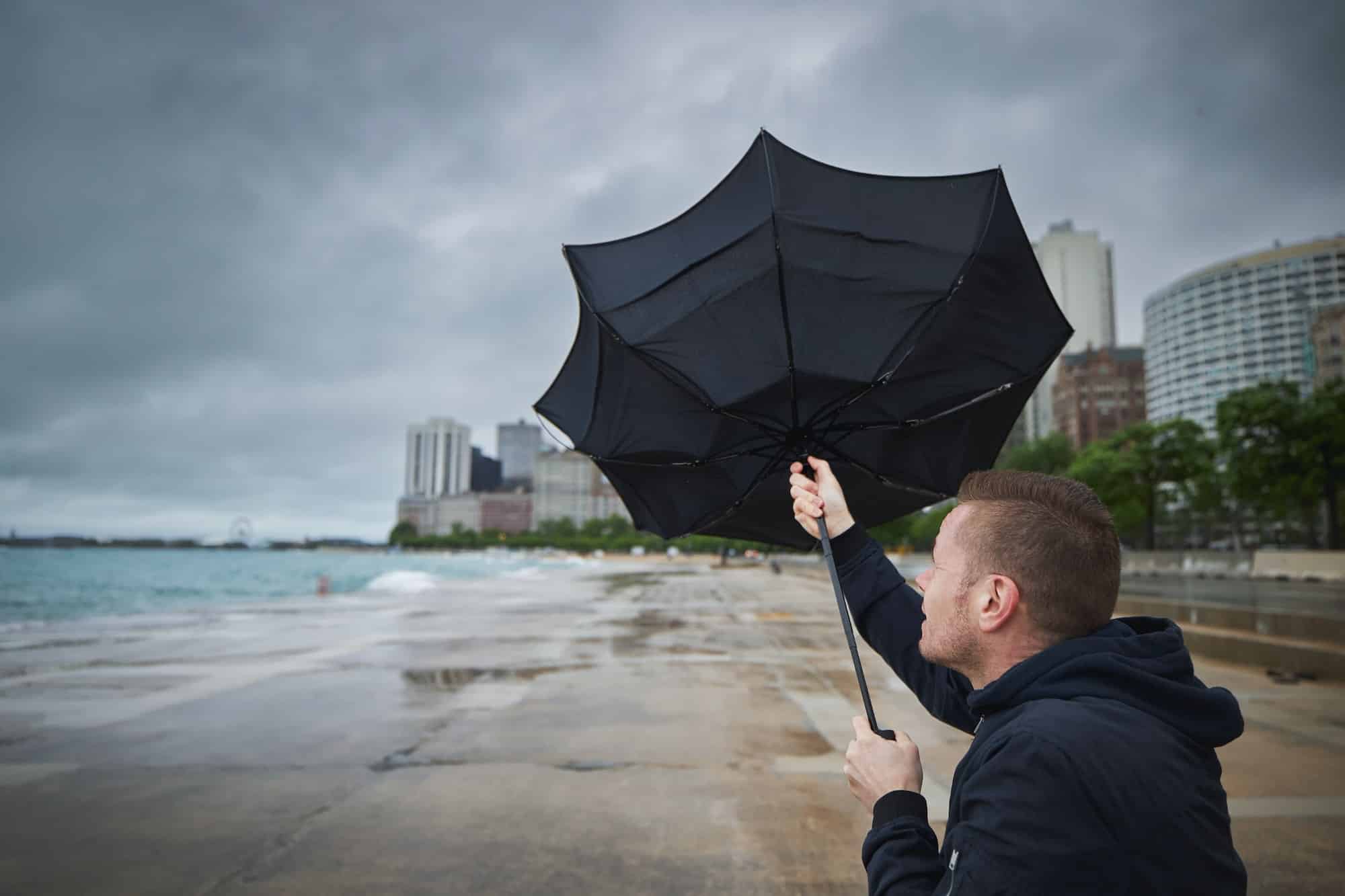 Man holding broken umbrella in strong wind