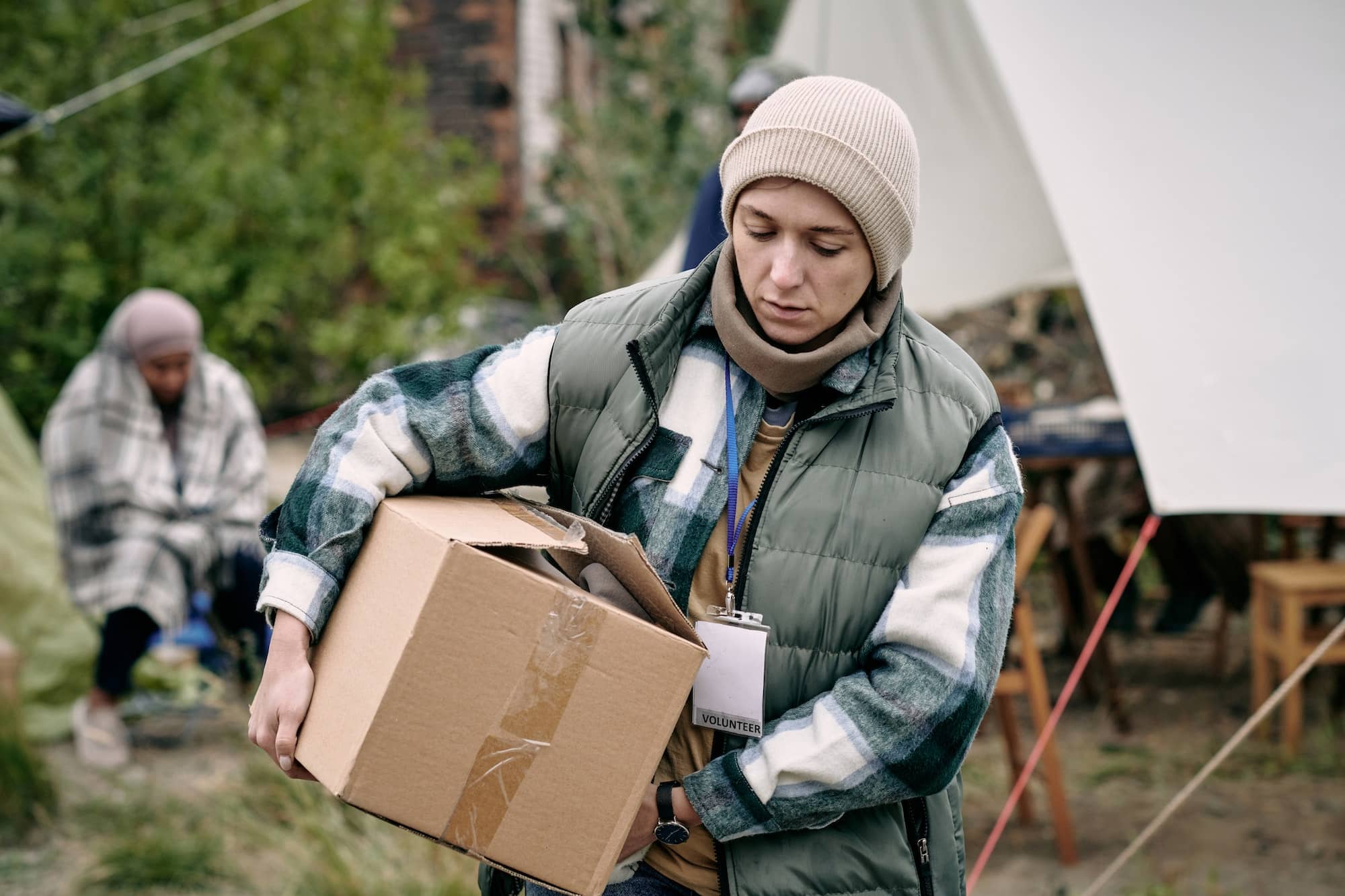 Young woman carrying box with clothes for refugees