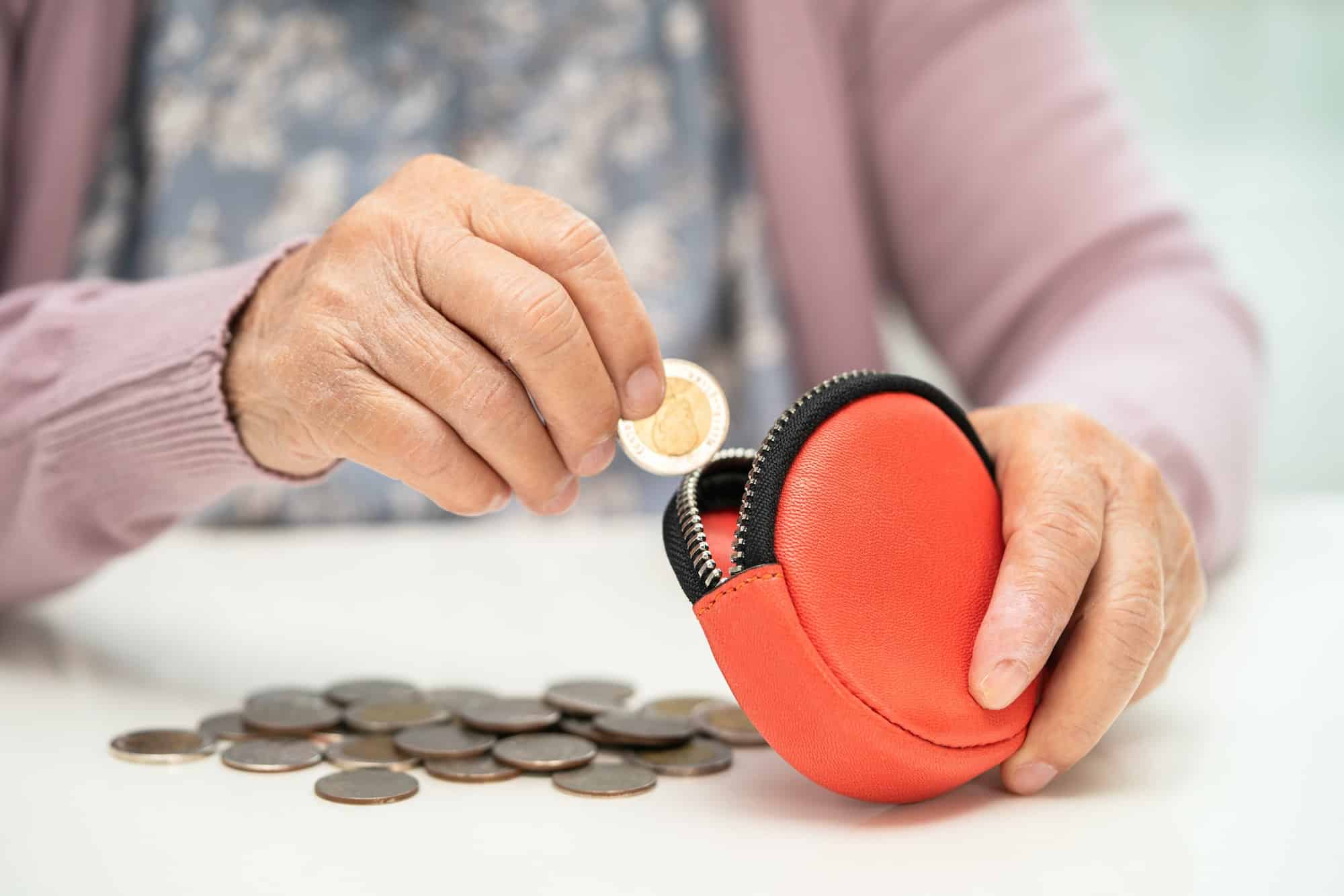 Asian elderlywoman holding counting coin money in purse. Poverty, saving problem in retirement.