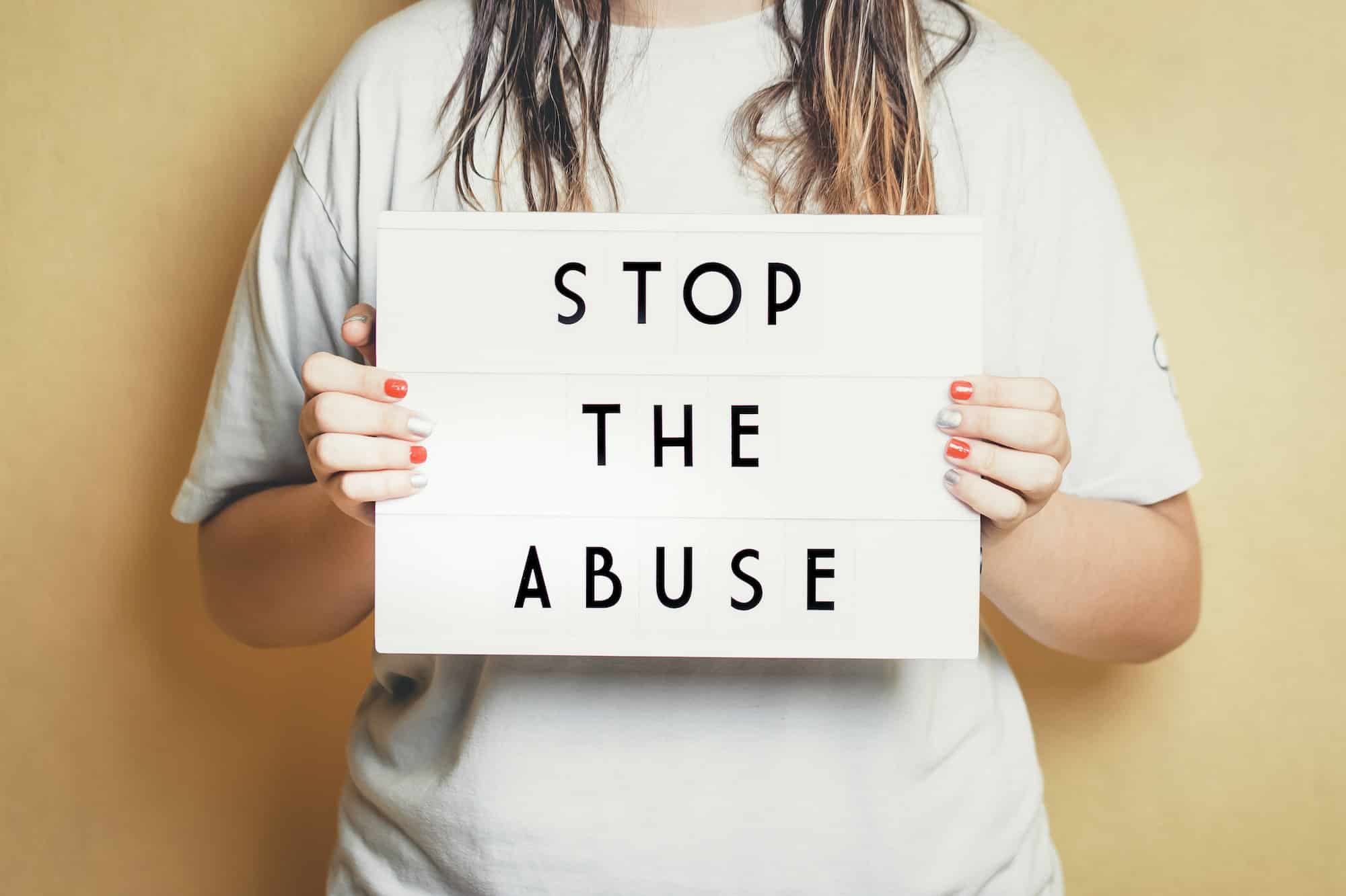 Girl holding a light box with the phrase "stop the abuse".