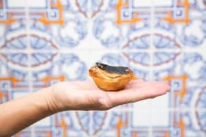 A hand holding a pastel de nata in Lisbon, Portugal.