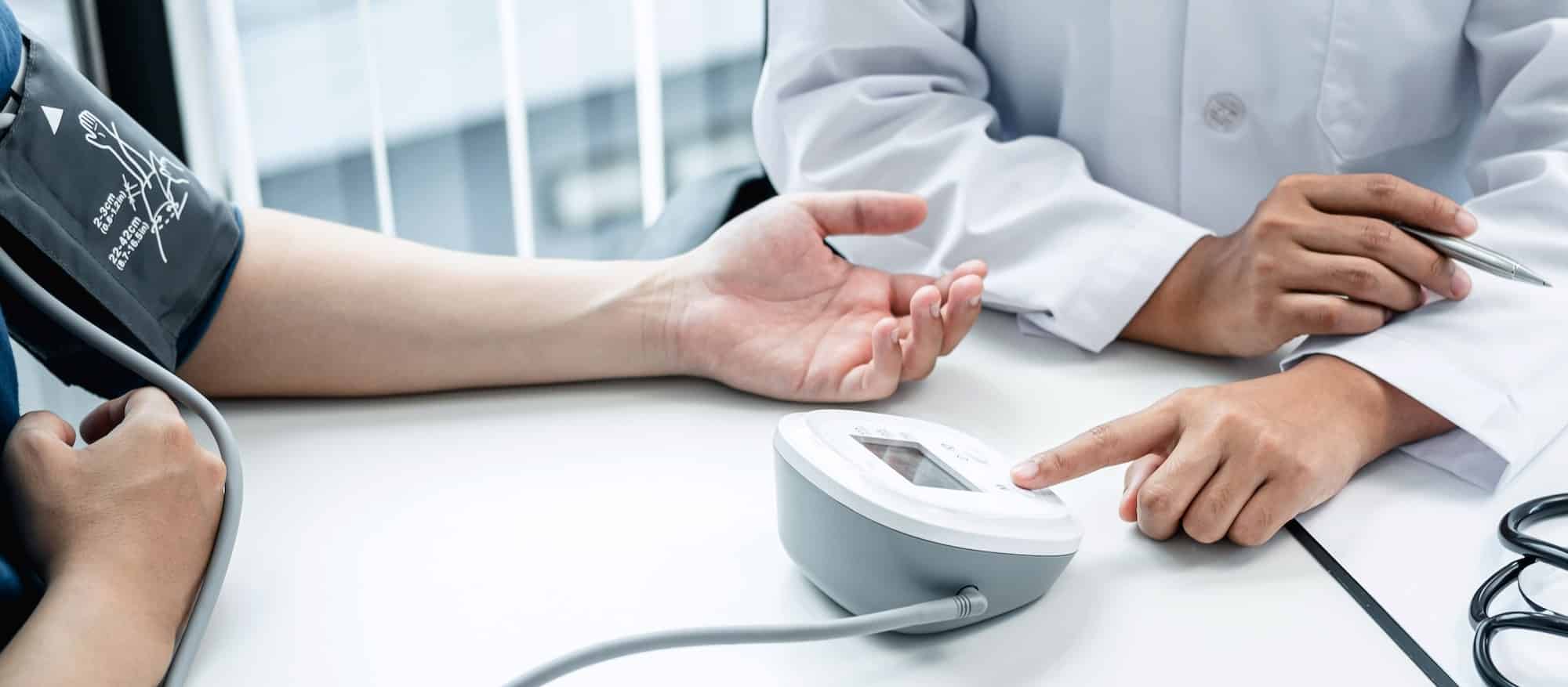 Doctor press blood pressure monitor to measure patient blood pressure