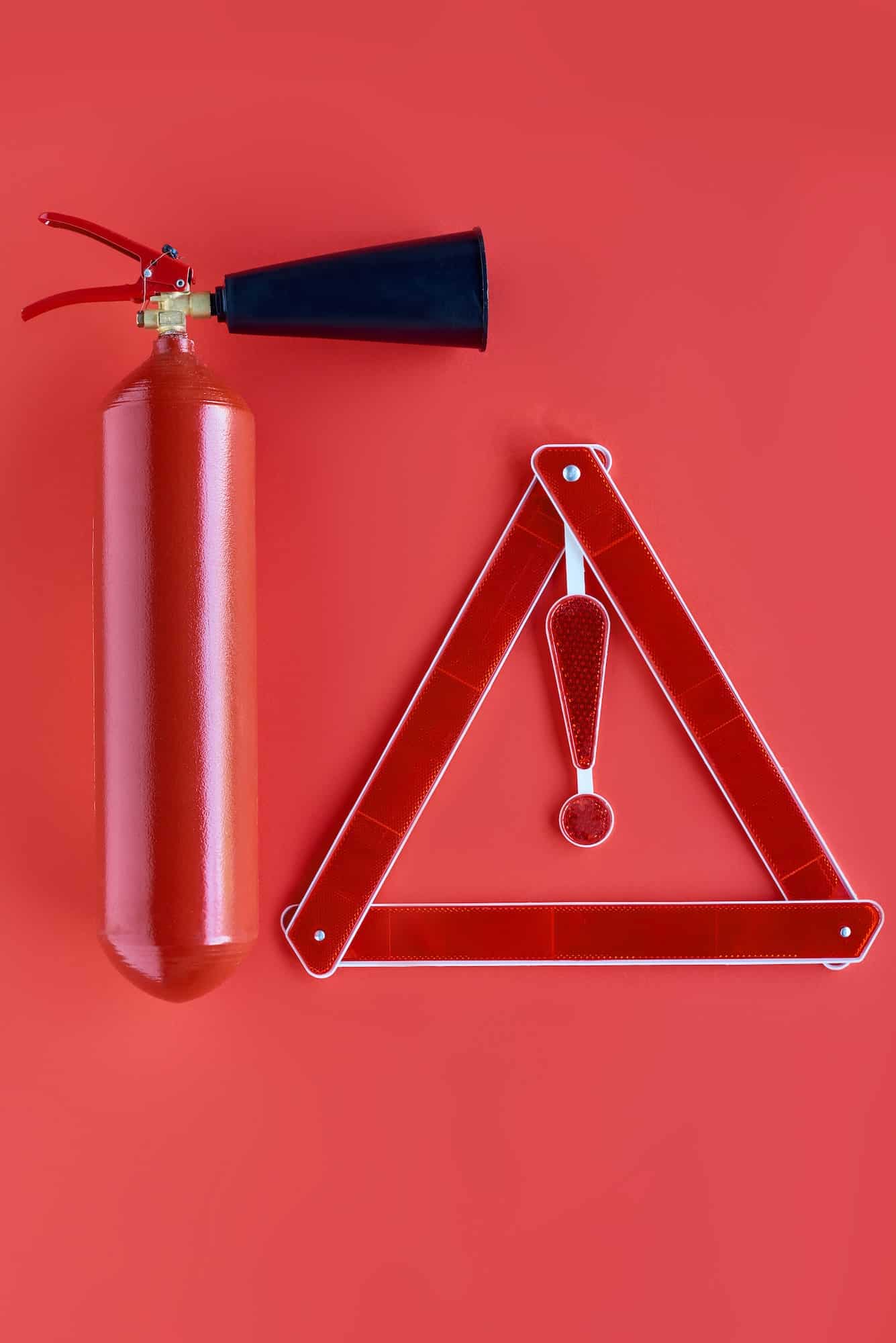 top view of fire extinguisher and warning triangle isolated on red