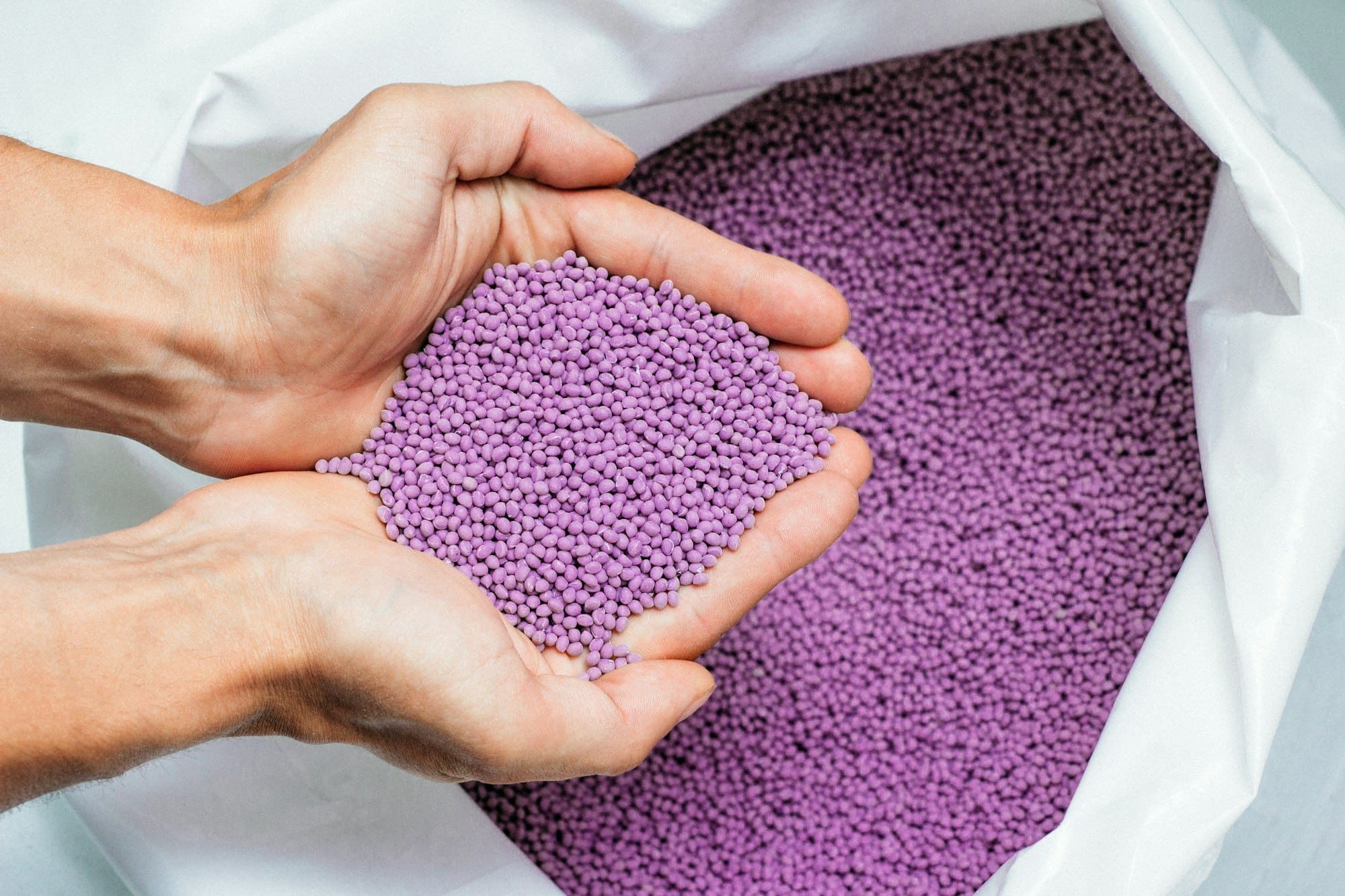 hands hold or touching biodegradable plastic pellets, plastic polymer granules