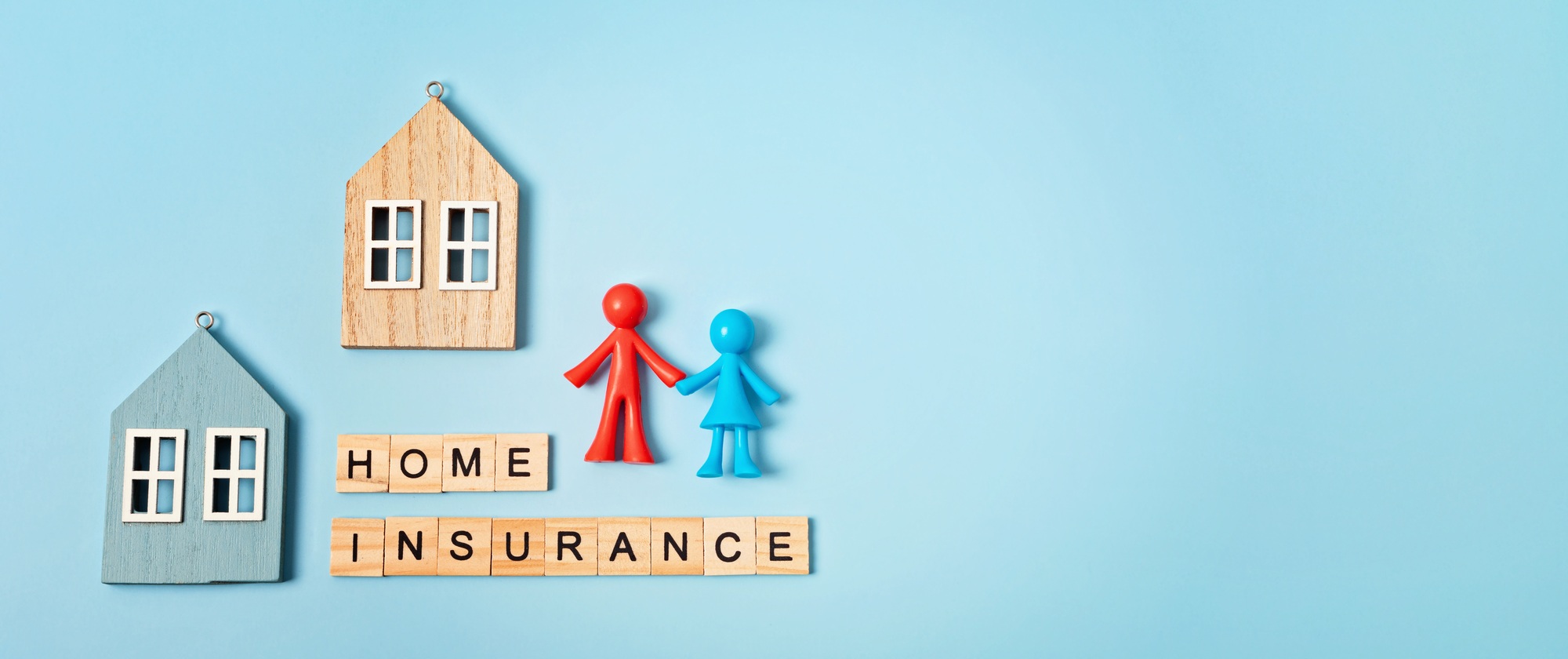 Home insurance message and wooden houses over blue background