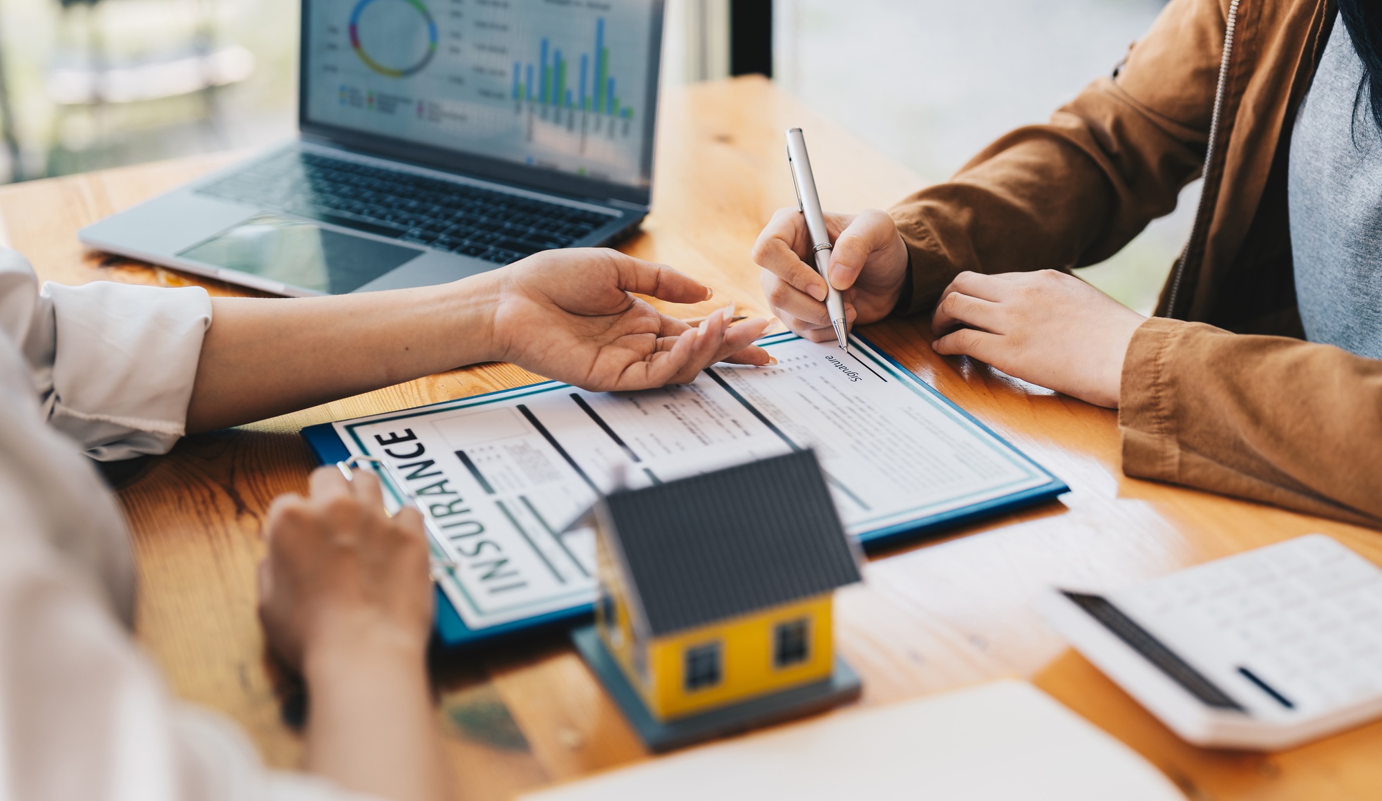 Real estate home are pointing to insurance contract signing and are explaining to customers at the